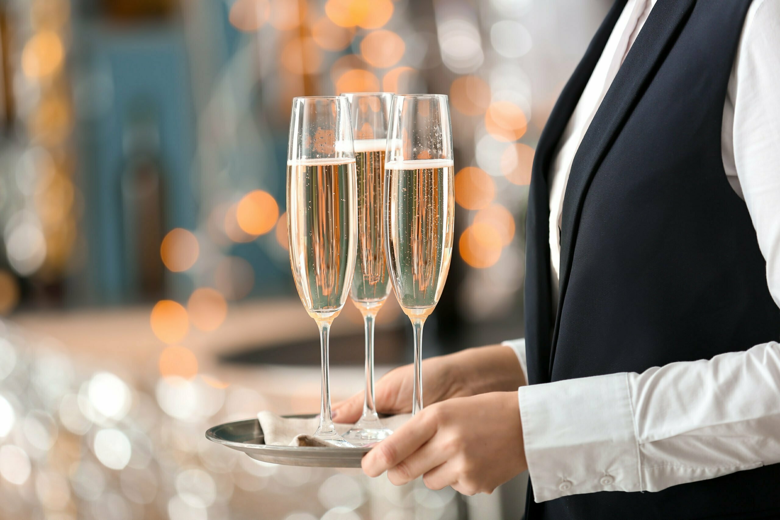 Waitress holding tray with glasses of champagne at party